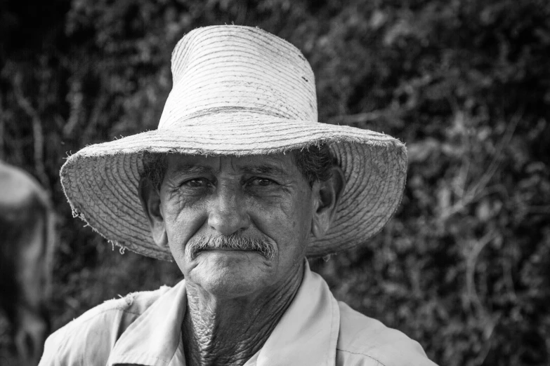 a man wearing a hat in front of trees