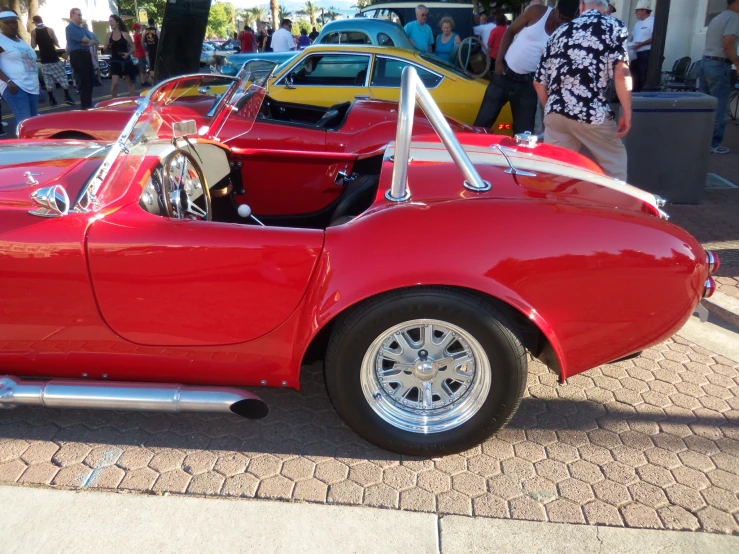 the red sports car is parked near the people on the sidewalk