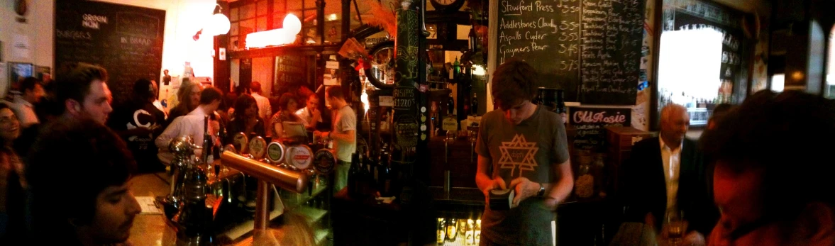 people are standing around a bar with bottles of alcohol