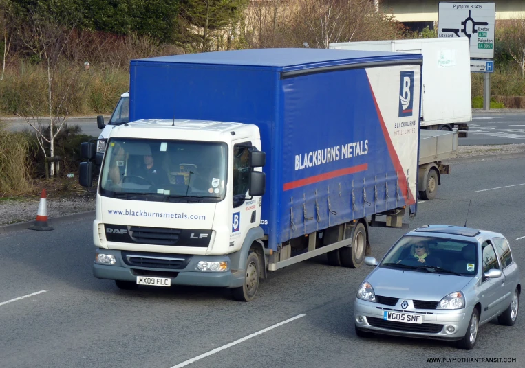 blue delivery truck driving on roadway near cars