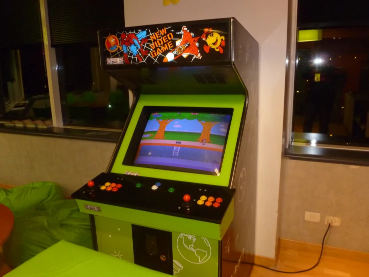 an arcade machine sitting on a wooden floor next to a window