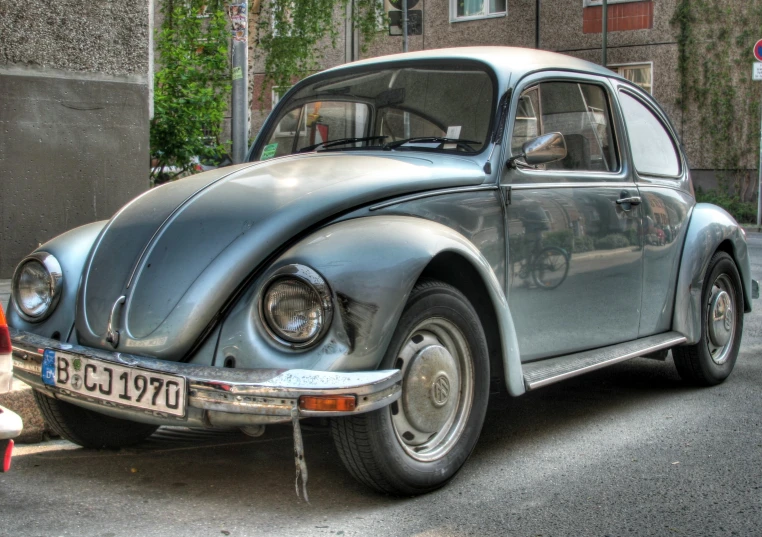 an old vintage silver beetle sits parked next to a curb