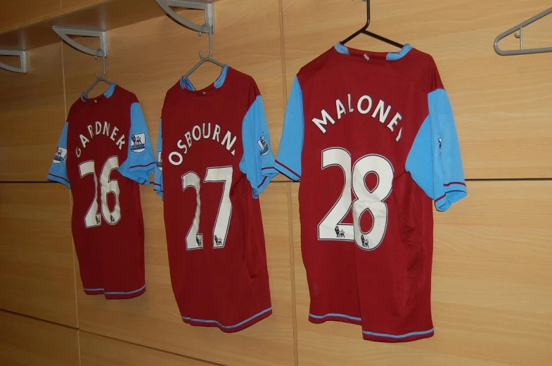 three jerseys hung up on clothes rack inside a dressing room