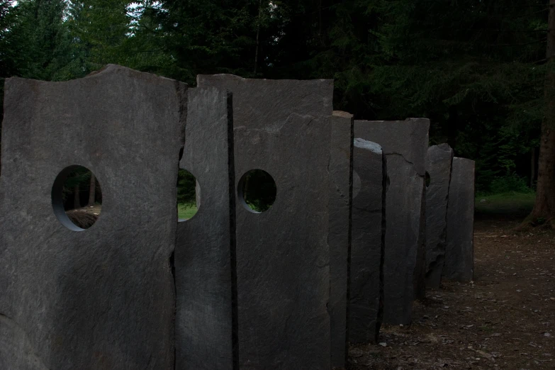 stone sculptures with holes and trees in the background