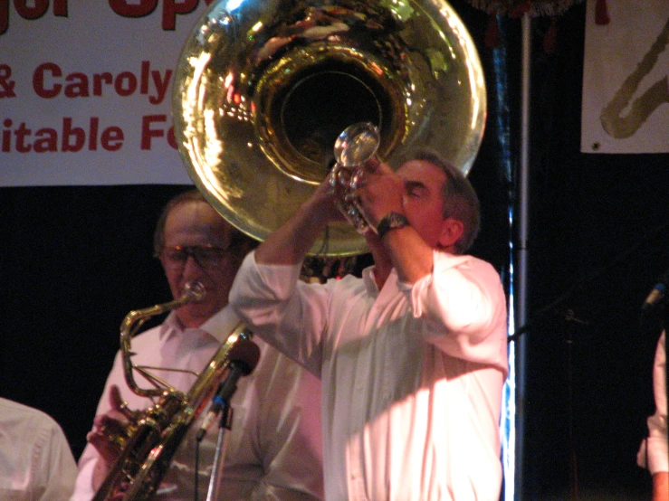 a man holding a trumpet on stage with a band nearby