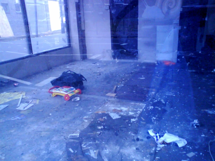 an abandoned room with a broken glass door and trash