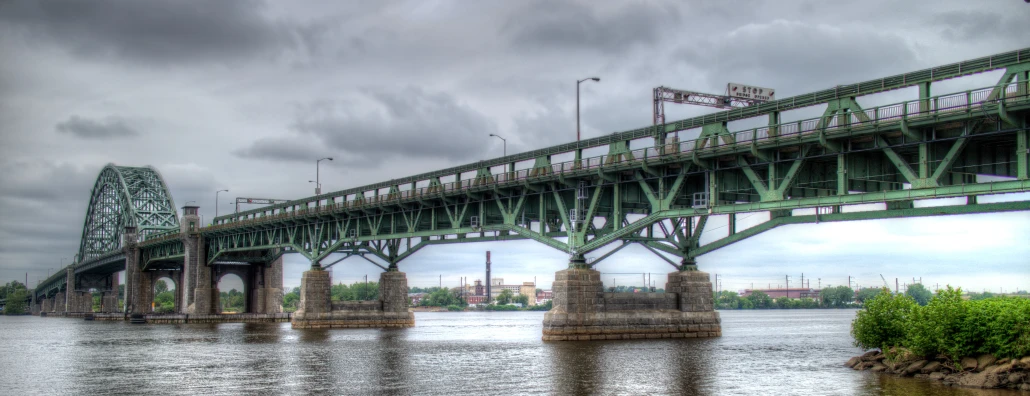 a green metal bridge spanning over water