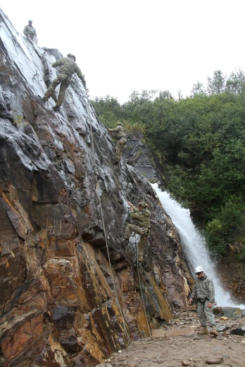 a person climbing a cliff by a waterfall