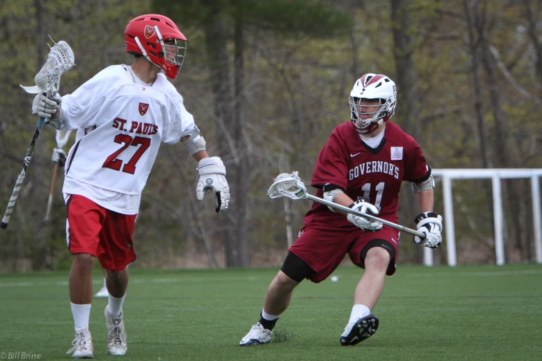 a couple of guys are running with their lacrosse sticks