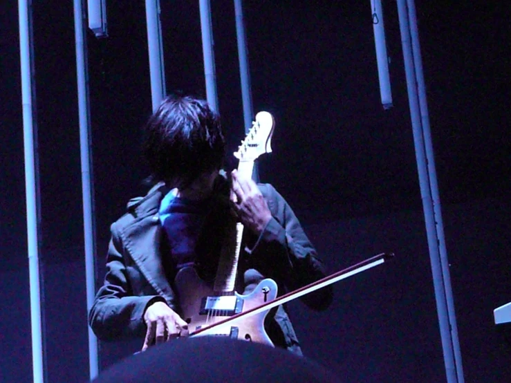 a man playing an electric guitar in the dark