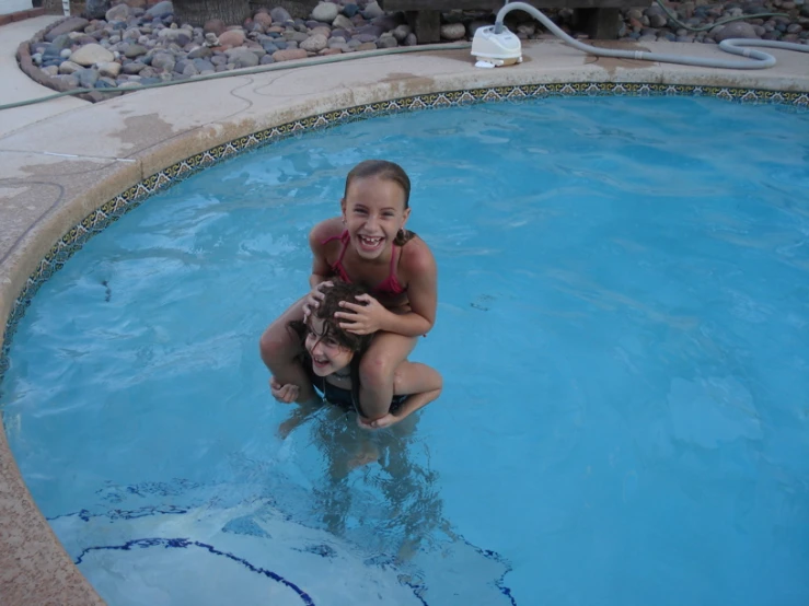 two girls play in a pool and laugh