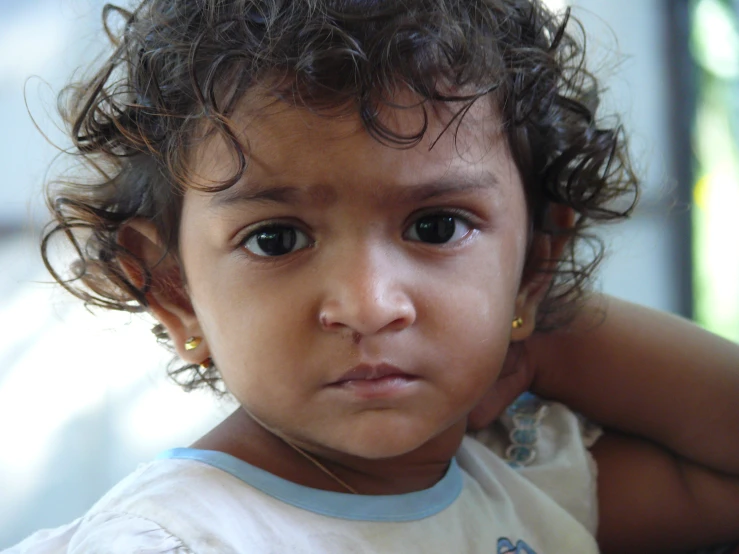 an adorable toddler girl with curly hair in a shirt