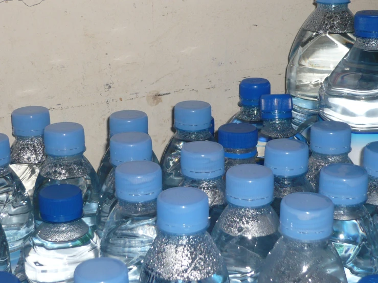several bottles of water are lined up in front of a wall
