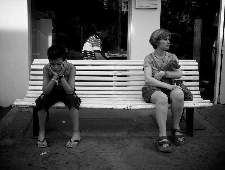 two people sitting on a bench in front of a store