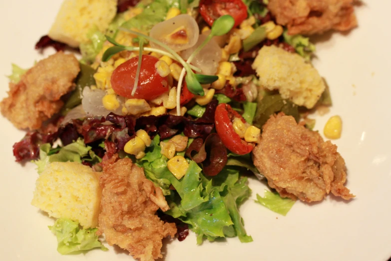 a plate with a salad that includes corn, tomatoes and other foods