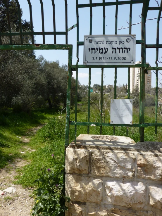 a sign on a green fence next to some grass