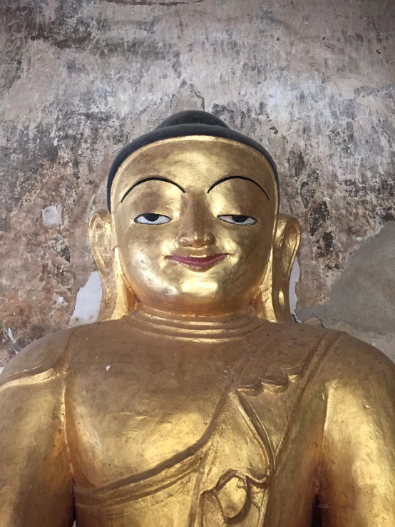 a golden buddha statue is seen with grey wallpaper
