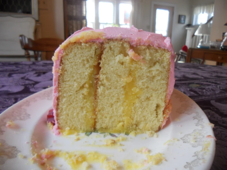 a half eaten piece of birthday cake with pink frosting
