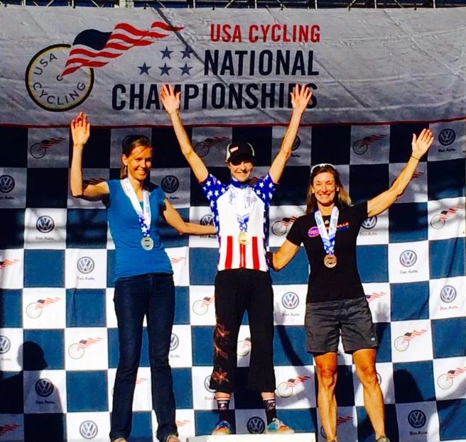 three women standing on a podium wearing black shorts