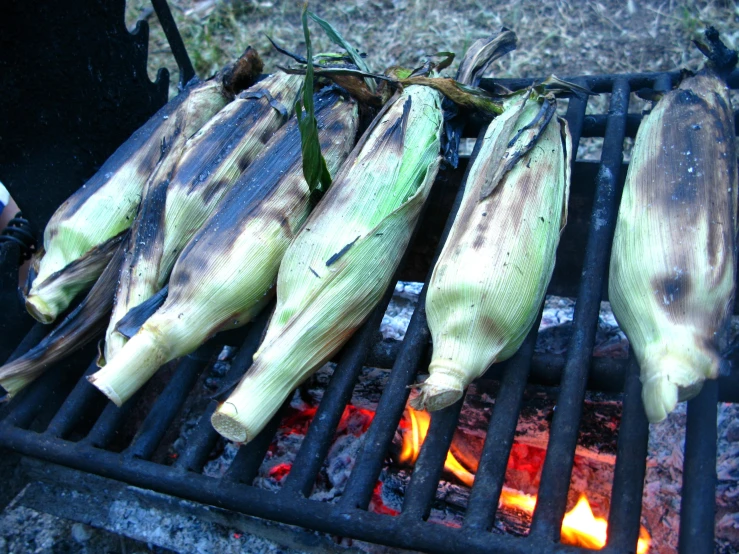 corn on the cob is being cooked over an open grill