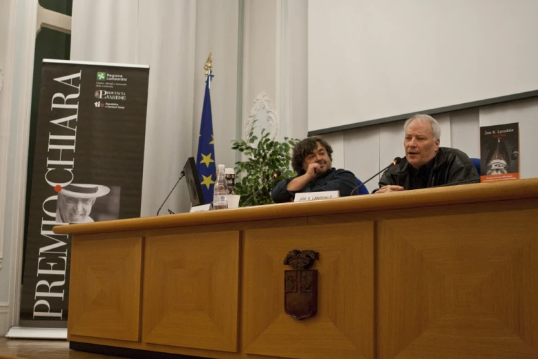 a woman and man sit at a table with papers