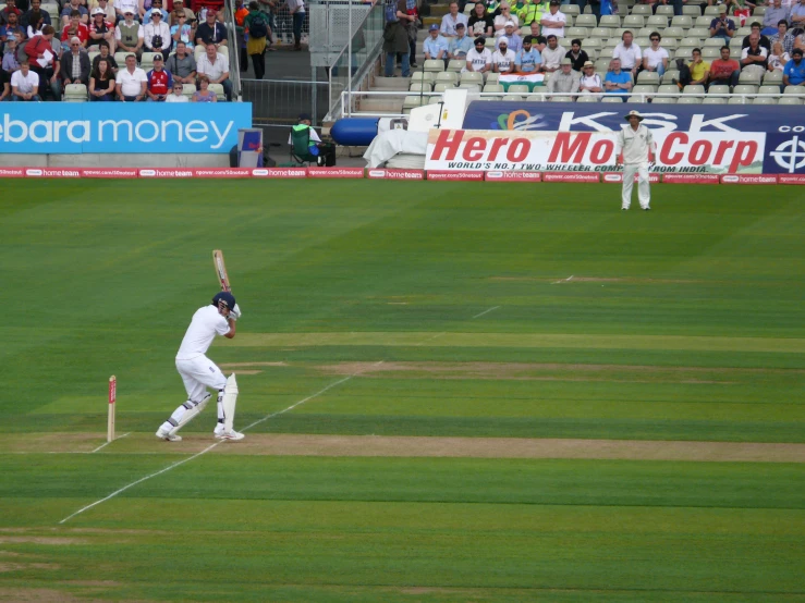 a man in white playing a game of cricket