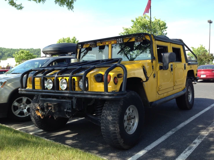 a yellow and black truck that is parked next to a white car