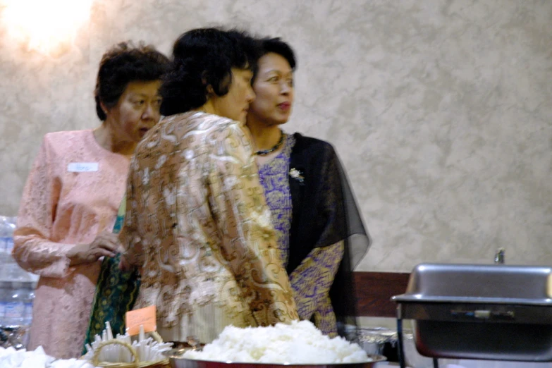 three people are standing around an enormous cake