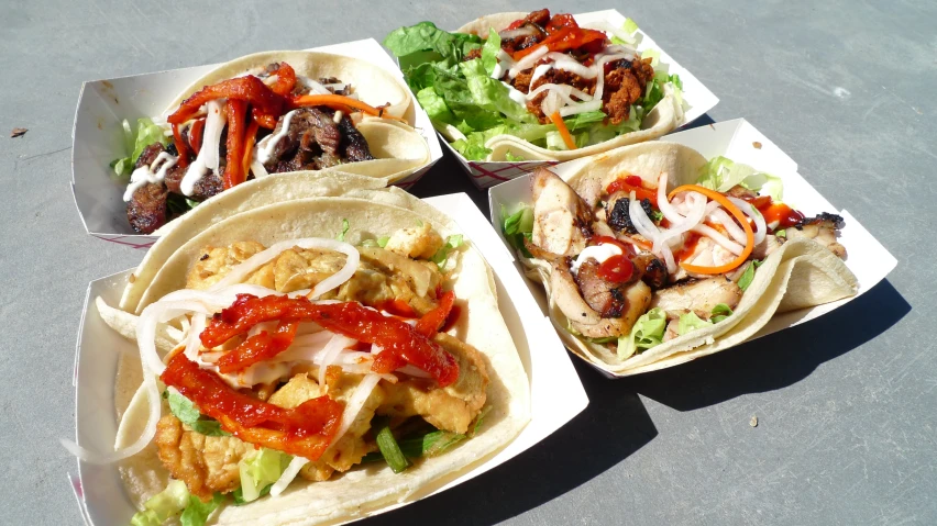 three tacos filled with food on top of a table