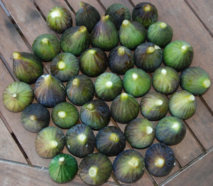 green figs sitting on top of wooden boards