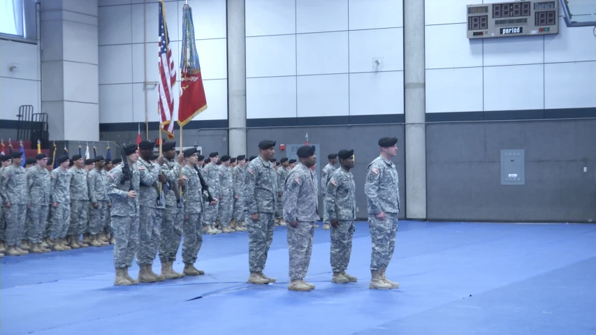 military members standing in formation in front of flags