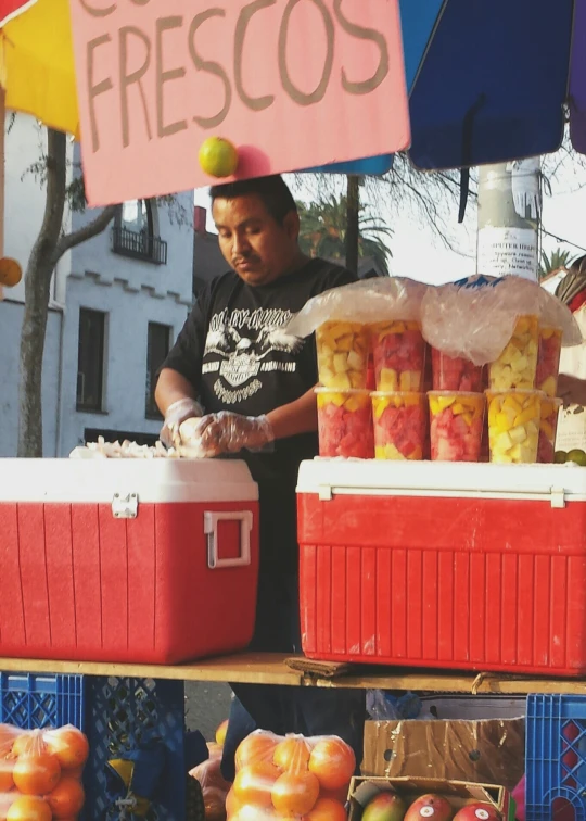 a man standing next to crates of fruit in front of a table