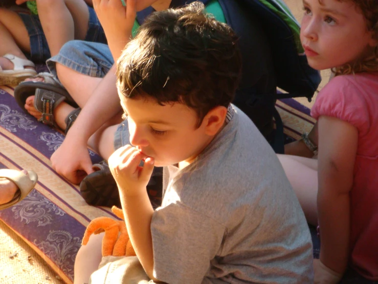 a small boy eating soing next to people