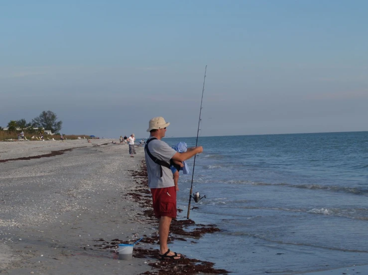 the man is holding his fishing pole on the beach
