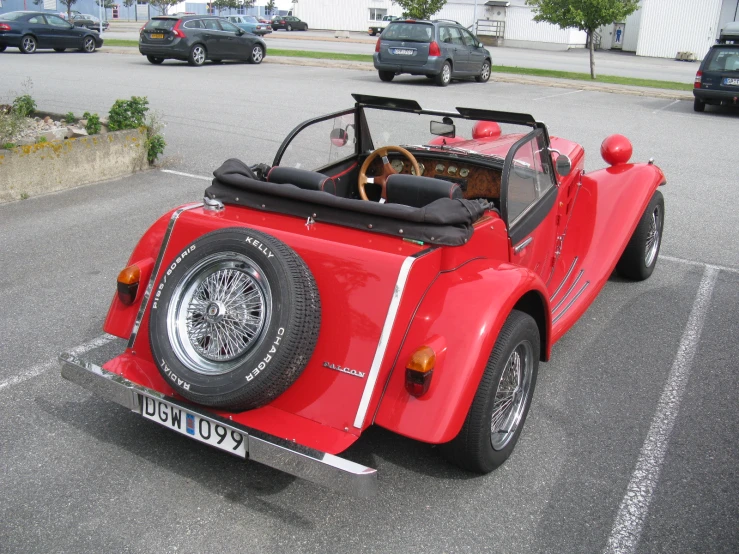 a very small red car in a parking lot