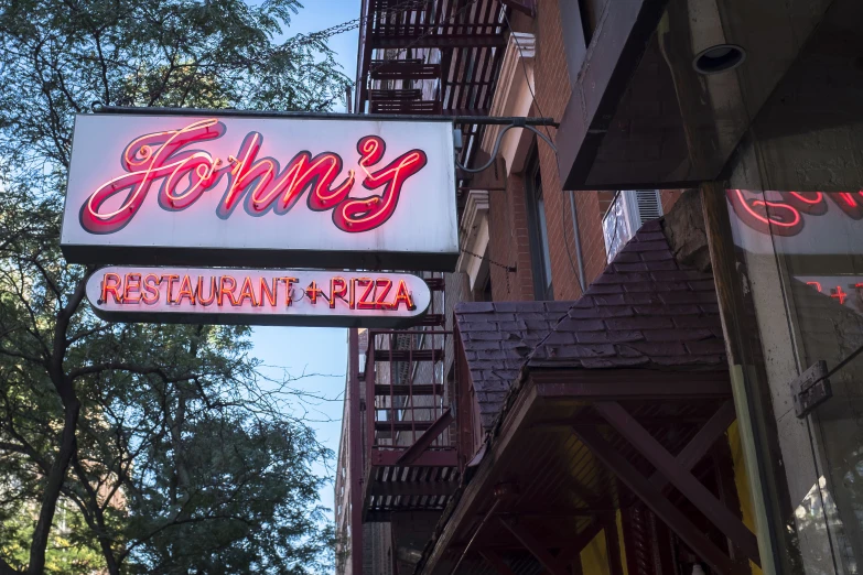 a neon sign in front of a restaurant on a brick building