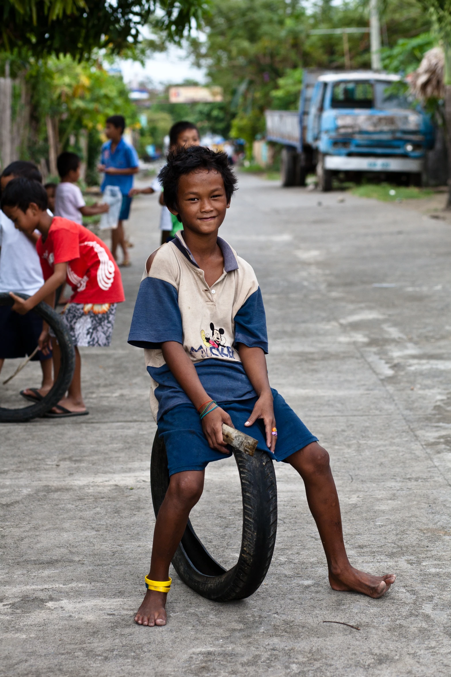 a boy is holding a tire on the street