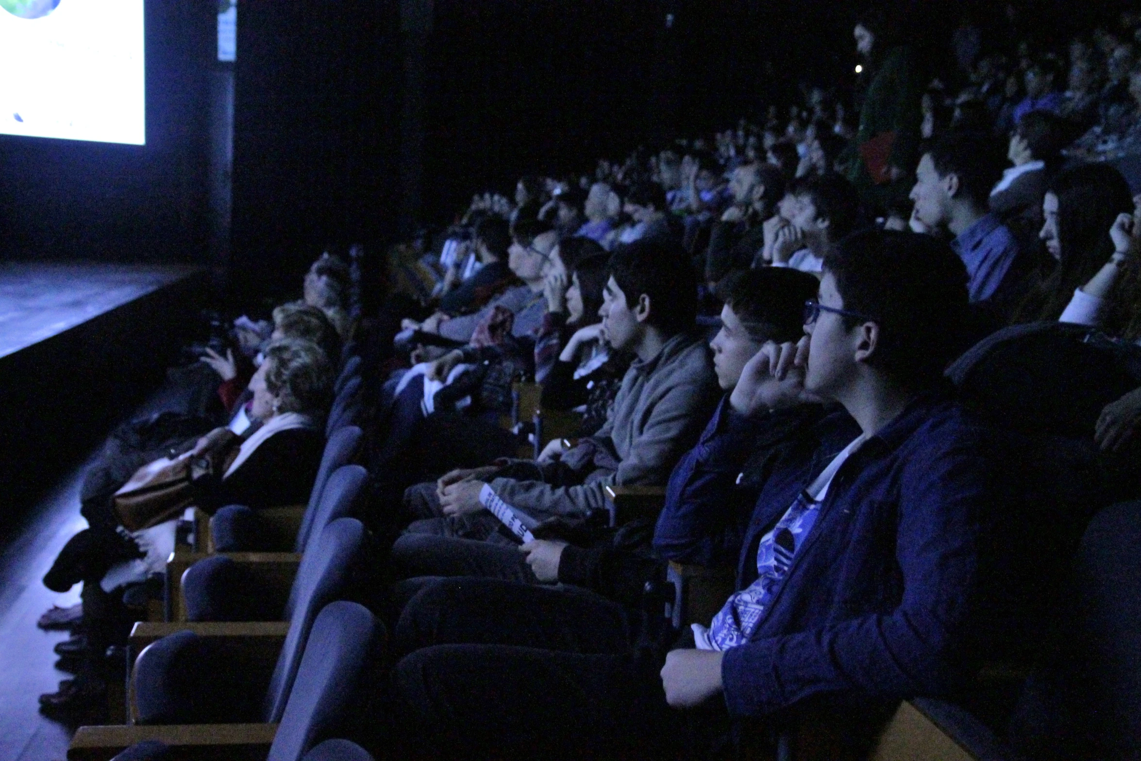 a group of people sitting in front of a screen watching a movie