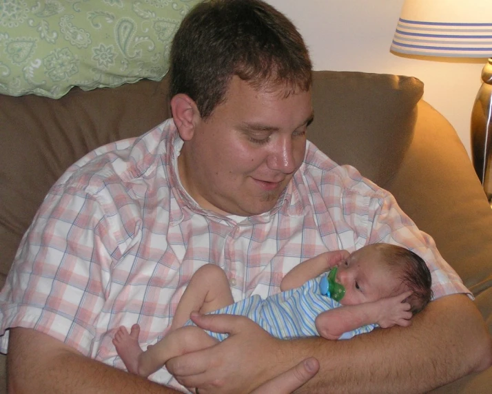 a man holding a baby, in the arms of his father