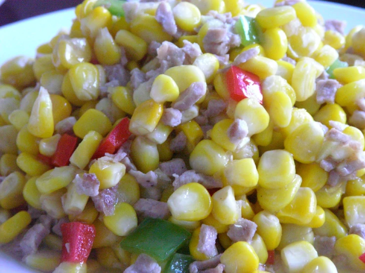 a white plate topped with corn, meat and veggies