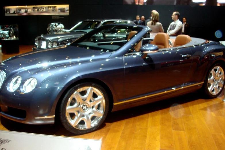 a blue convertible sits on display at an event