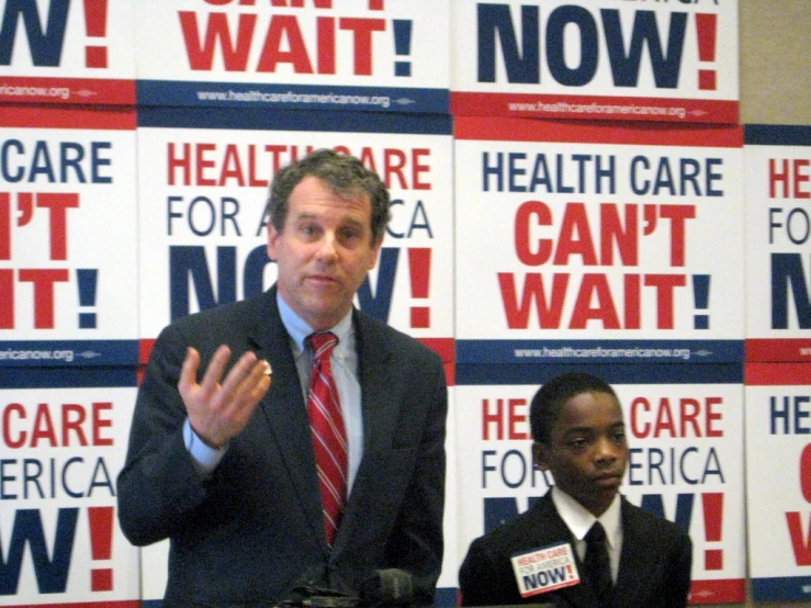 a man is speaking in front of a backdrop