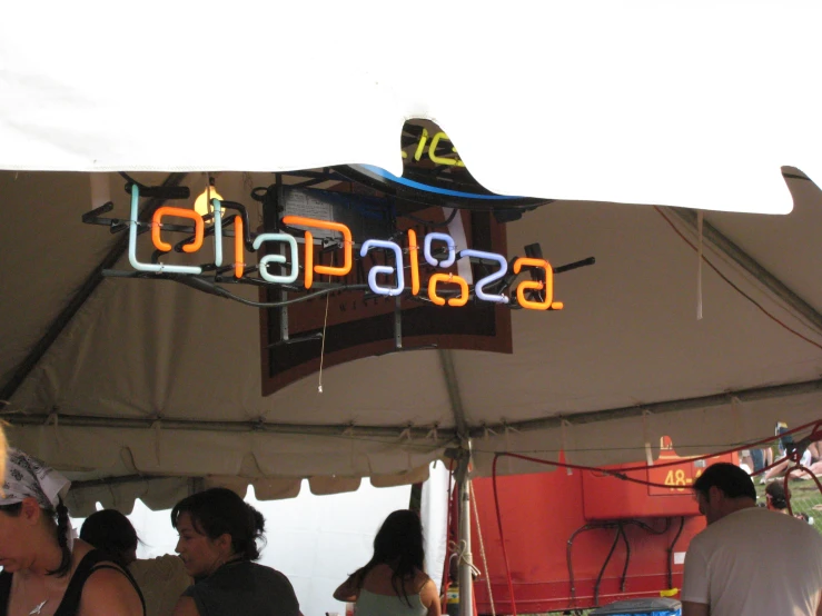 people are under a canopy with an illuminated sign