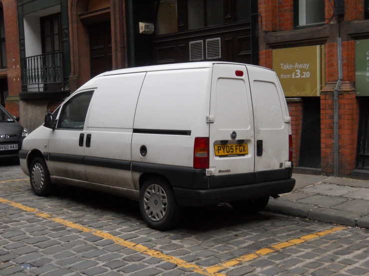 a small white van parked in front of a red brick building