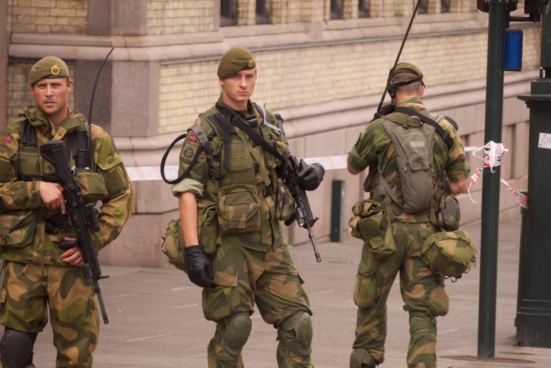 men in uniforms walking with weapons on their backs
