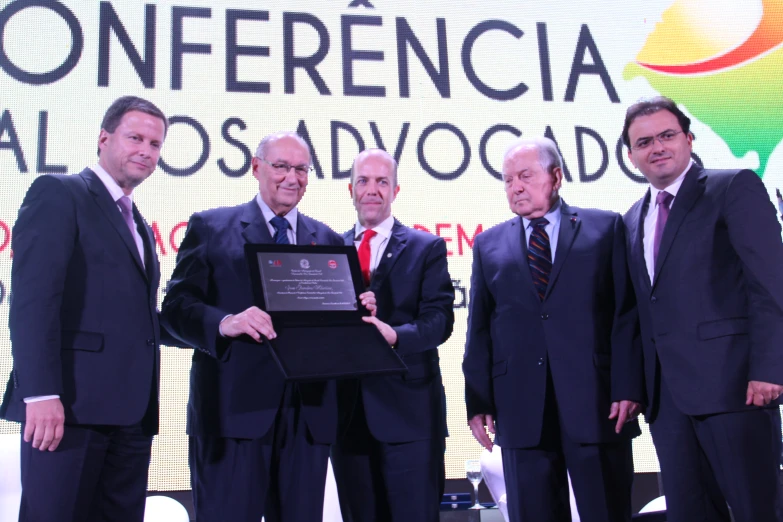 several men are holding up a plaque on stage