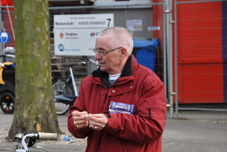 a man in a red jacket is standing near a bicycle