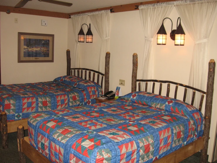 two beds with colorful blankets next to a window