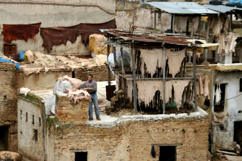 a man standing on a small dirty roof next to buildings