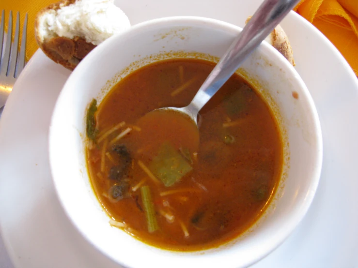 the bowl of soup is on the plate next to the fork